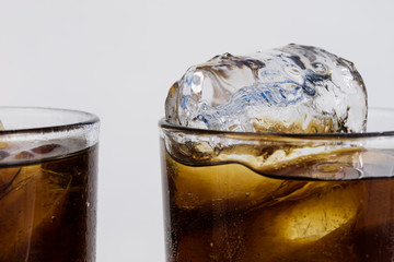 Cold drink with ice in a glass on a white table. A way to cool down on hot days.