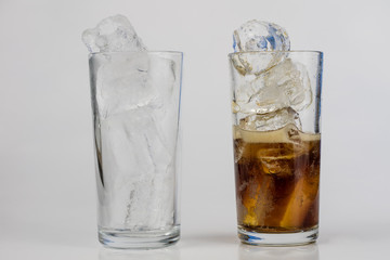 Cold drink with ice in a glass on a white table. A way to cool down on hot days.