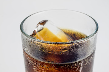 Cold drink with ice in a glass on a white table. A way to cool down on hot days.