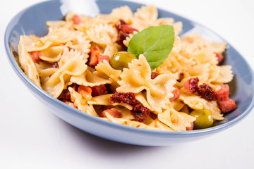 Farfalle pasta with sun dried tomato, ham and olives decorated with fresh mint
