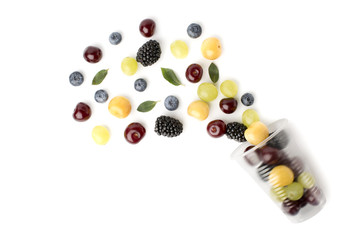 Colorful cherries with leaves poured out a plastic Cup on a white background.