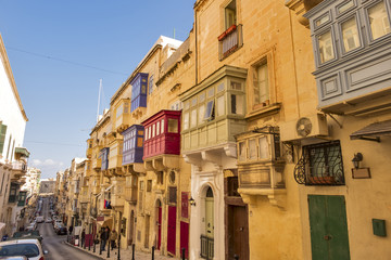 Fototapeta premium Old narrow street with colorful balconies in historical part of Valletta in Malta