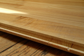 An image of an old wooden floor and a new parquet board.