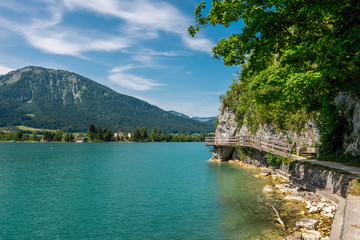 Fototapeta premium Jetty on the edge of the turquoise lake called Wolfgangsee mountains in the background and clouds on the sky