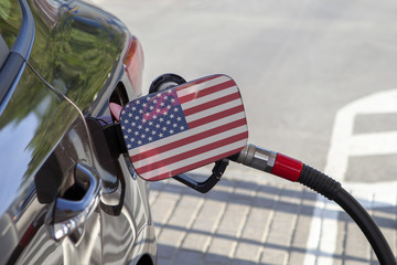 Fueling car with petrol pump at a gas station.