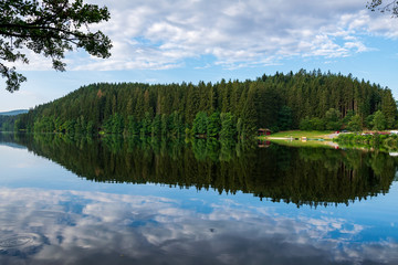 Lake with Reflection on the Water and Trees in the background and Clouds on the sky in the bavarian forest