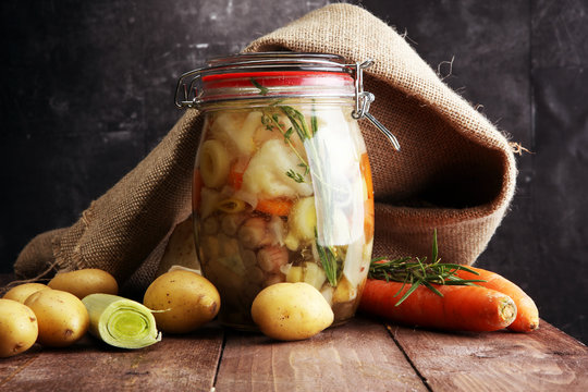 Jar with variety of pickled vegetables. Broth, Carrots, field garlic, parsley in glas. Preserved food