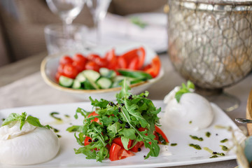 Italian Caprese salad. burrata cheese, tomatoes and basil herb leaves. Balsamic vinegar arranged on white plate