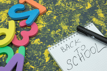 A layout of notepad, pencils, markers and clips on a wooden background with a place for an inscription.