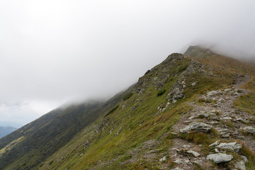 Fototapeta na wymiar mountain ridge covered by half with the cloud