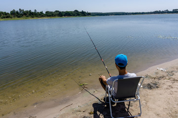 boy teenager is fishing on the fishing rod in summer.