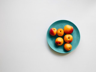 Nectarine Top view Six nectarines are lying on a blue plate on a white background Trendy minimalist photo for posters, banners with copy space