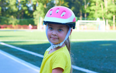 The little girl rolls on rollers in a protective helmet.