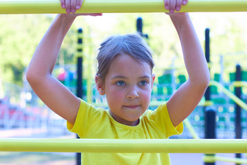 Obraz premium A little girl on the playground climbs the stairs.