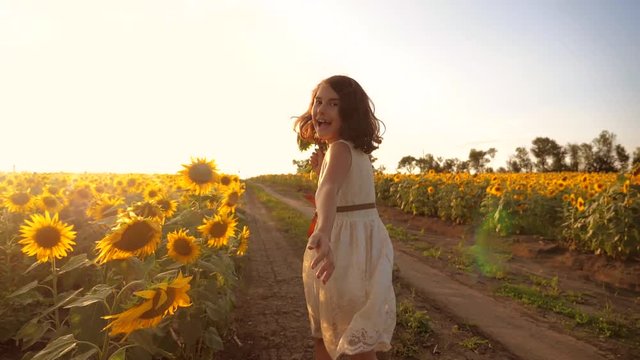 little girl running across the field with sunflowers at sunset. slow motion video. girl runner in the field at lifestyle sunset sunflowers. girl sunlight runs the concept of sunflowers