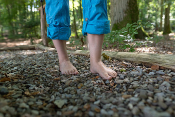 zwei weibliche Füße gehen über Kieselsteine
