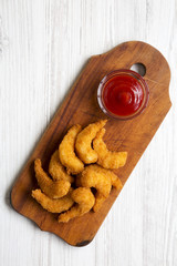 Fried shrimps tempura with sauce on rustic wooden board over white wooden background, view from above. Closeup.