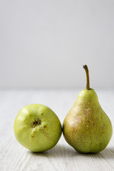 Two pears on a white wooden table, side view. Closeup.