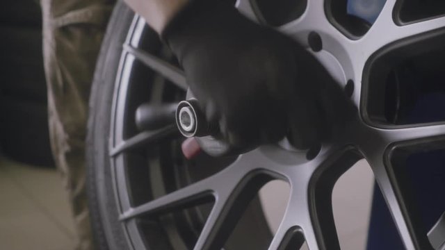 man balances the wheel after tire fitting