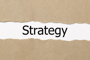 The word strategy appearing behind torn paper. 