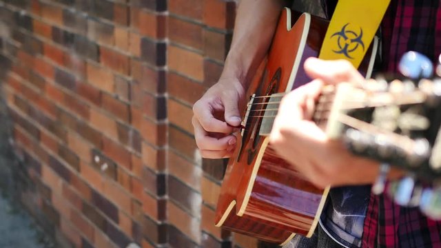 Plucking guitar outside of brick building