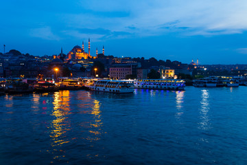 Naklejka premium Night view of Istanbul. Panorama cityscape of famous tourist destination Golden Horn bay part of Bosphorus strait. Travel illuminated landscape Bosporus, Turkey, Europe and Asia.