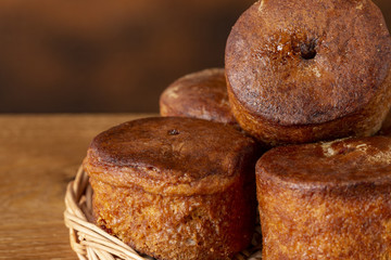Small cupcakes without cream on a wooden basket. Background is brown. Copy space.