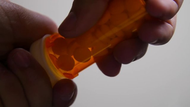 Person Opens Pill Bottle and Pours Pills On To Camera in Slow Motion