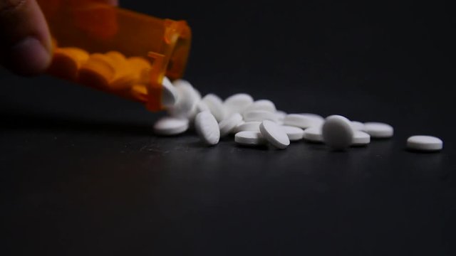 Hand Pours Out Bottle Of Pills On To Table In Slow Motion