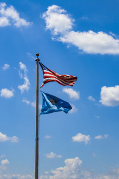USA and Oklahoma flags flying against a very blue sky with fluffy white clouds on a windy day
