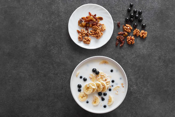 .Bowl of oatmeal porridge with banana and blueberry on vintage table top view in flat lay style. Healthy breakfast and diet food..