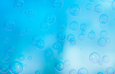 Radiant soap bubbles on blurred blue background. Rainbow soap bubble.