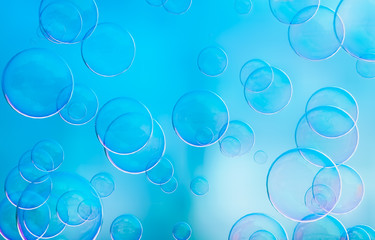Radiant soap bubbles on blurred blue background. Rainbow soap bubble.