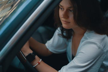 Close-up preety woman portrait holding hands on the steering whe