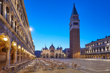 Fototapeta na wymiar San Marco square illuminated in the early morning, empty tables and chairs in Italy