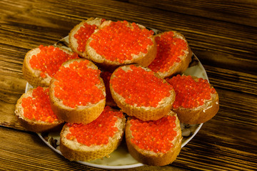 Sandwiches with red caviar on wooden table