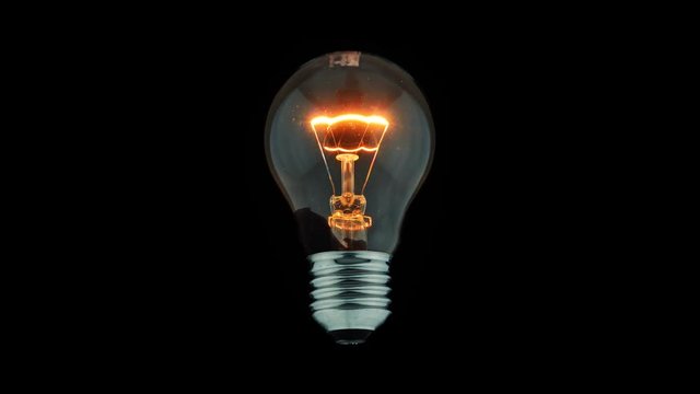 Tungsten light bulb lamp blinking and color ink flowing over black background
