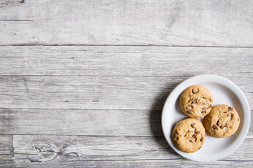 Tasty cookies with pieces of chocolate on wooden grey background, copy space, nobody.