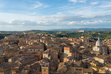 Fototapeta na wymiar Aerial and top view scenery of old ancient Tuscany region town and medieval brick buildings with green range mountain landscape background in Siena, Italy 
