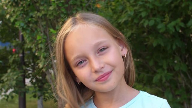 Adorable girl touching blonde hair and looking at camera, reversed