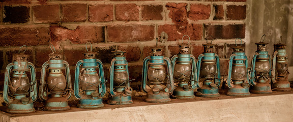 Old kerosene lanterns lined up against a brick wall