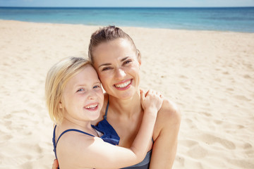 happy modern mother and child in swimwear on seashore