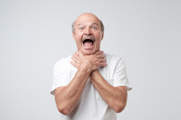 Mature european man in white tshirt shouting and suffocate because painful strangle. Health problem.