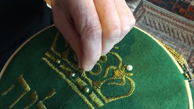 Woman embroidery at home. Embroidery is the craft of decorating fabric or other materials using a needle to apply thread or yarn. Close-up details.