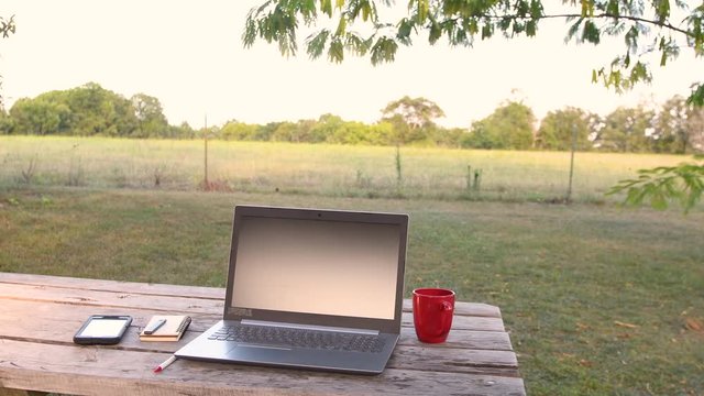 Laptop computer sitting on picnic table outside