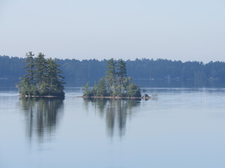 Fototapeta na wymiar Reflection of islands on a calm lake in the morning 