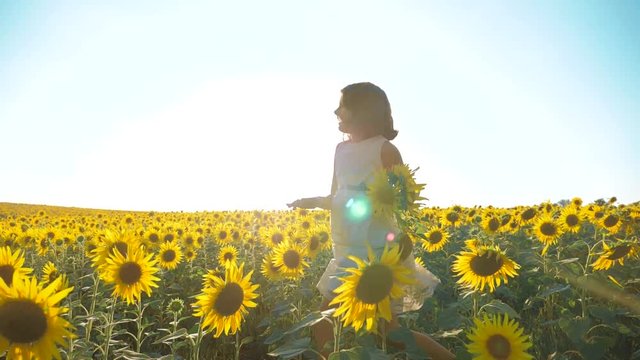 Happy little girl running happy free across the field with sunflowers. slow motion video. smelling big sunflower on lifestyle summer field. Delight of a pleasant smell. Summer holiday. concept