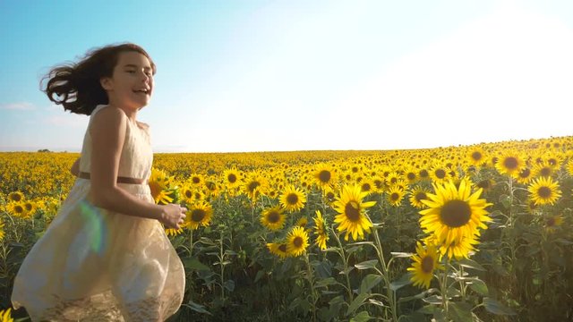Happy little girl lifestyle running happy free across the field with sunflowers. slow motion video . smelling big sunflower on summer field. Delight of a pleasant smell. Summer holiday. concept