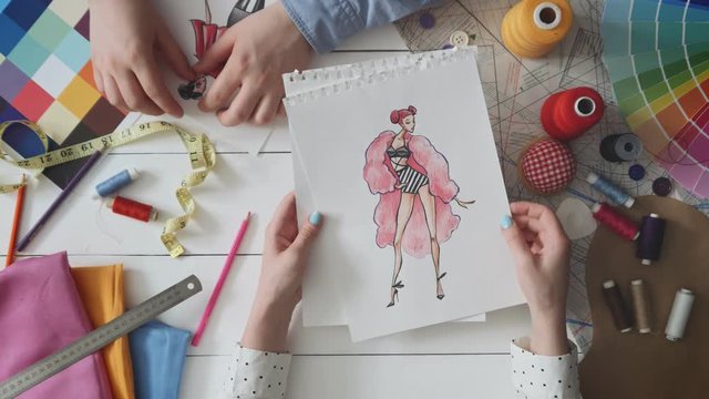 Small team of fashion designers choosing sketches for the new dress