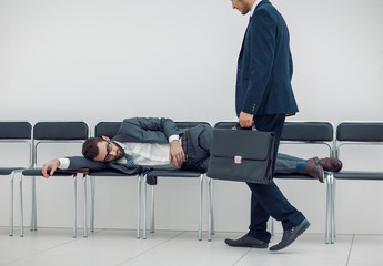 businessman walks past a sleeping visitor